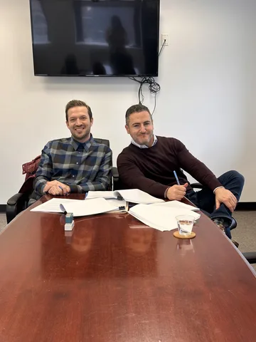 Bruce Elia Jr. seated at a conference table with a client after finalizing their deal